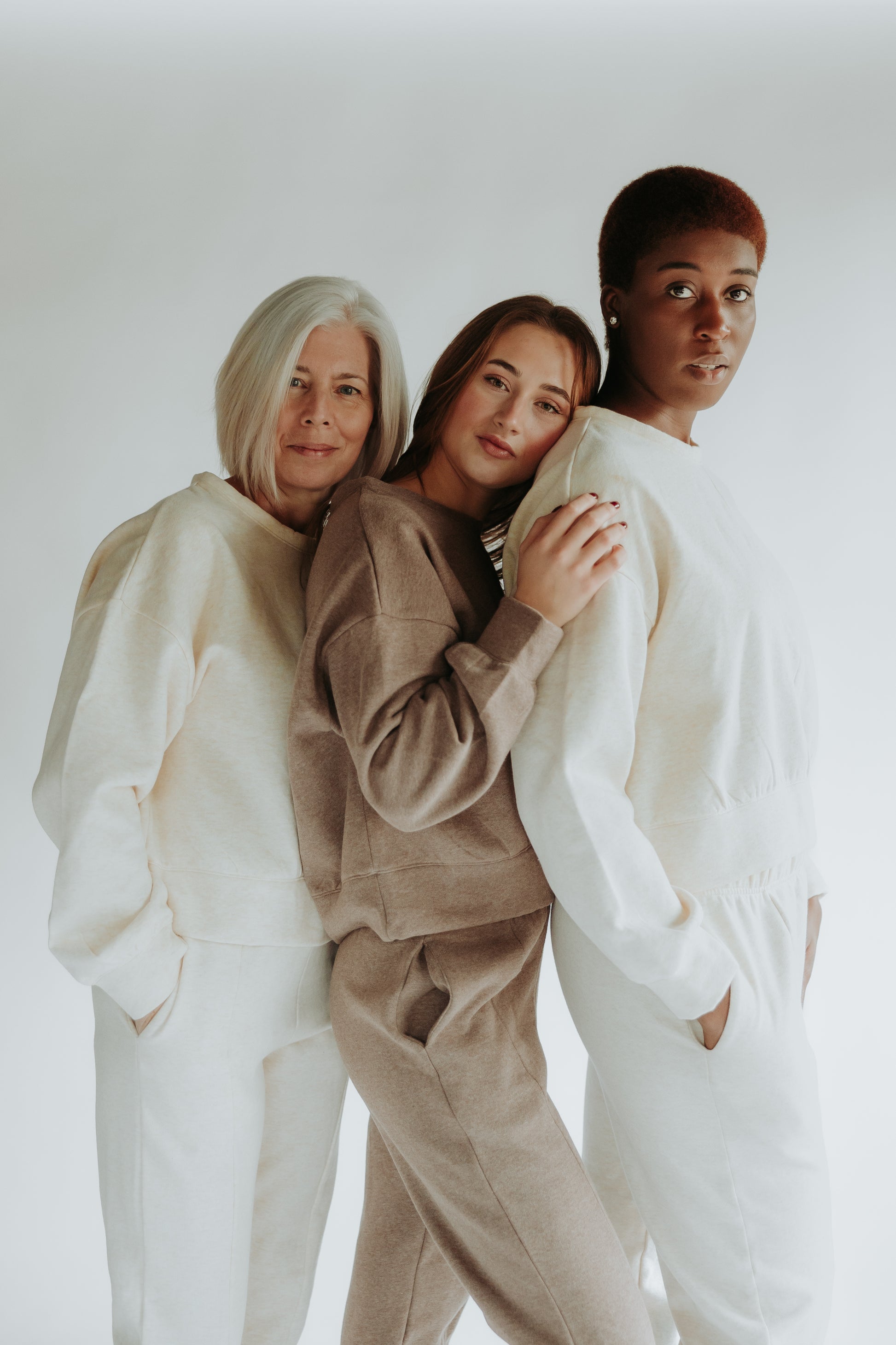Three women are looking at the camera and wearing the classic fleece set in the color chocolate brown and beige